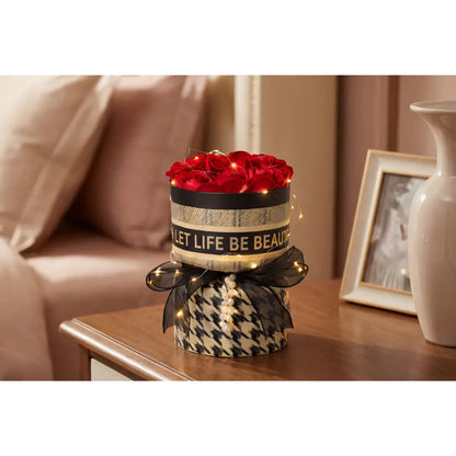 Decoratieve rozenbox met rode rozen en LED verlichting op houten tafel in sfeervol interieur