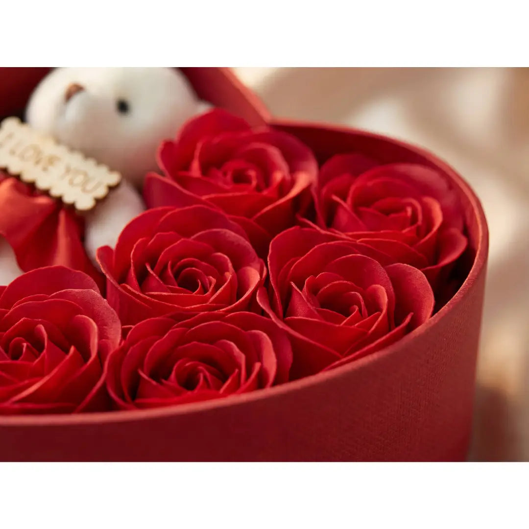 Close-up van rode rozen in hartvormige geschenkdoos met teddybeer op de achtergrond