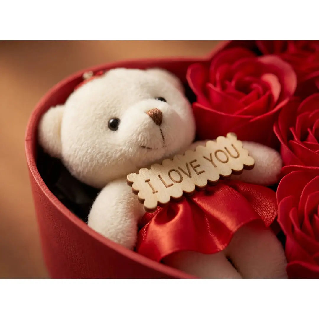 Close-up van witte teddybeer met I love you bordje in hartvormige rozenbox
